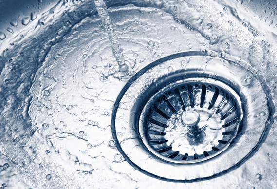 Close-up of water flowing from faucet into sink, showcasing the dynamic swirl around the drain.